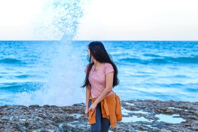 Woman standing at beach against sky