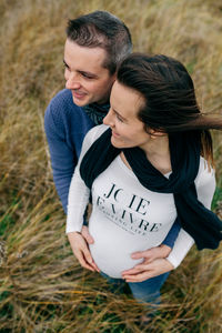 Pregnant woman with man standing on field