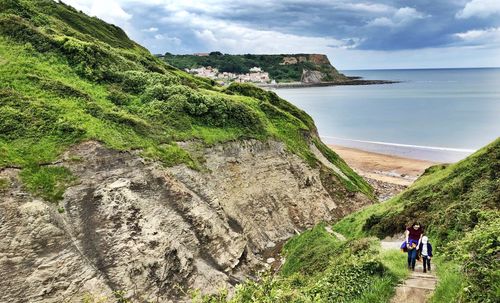 Mother and daughter climbing mountain by beach