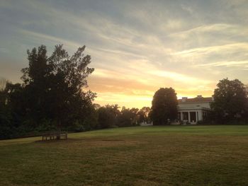 Scenic view of grassy field against sky at sunset