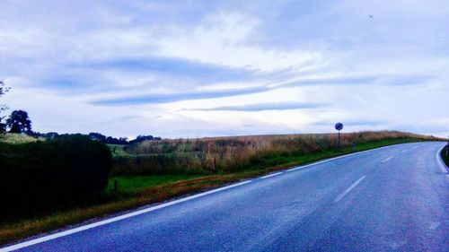 Empty road by landscape against sky