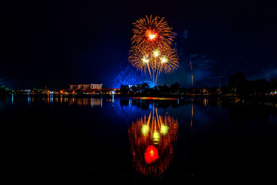 Firework display over lake against sky at night