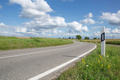 Road amidst green landscape against sky