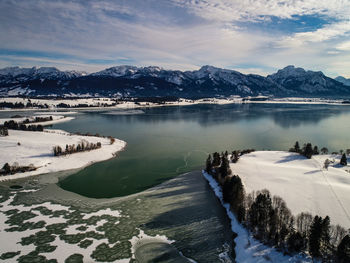 Scenic view of lake by snowcapped mountains against sky