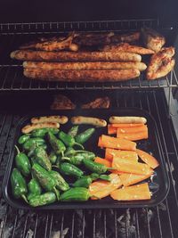 High angle view of vegetables and sausages on barbecue grill