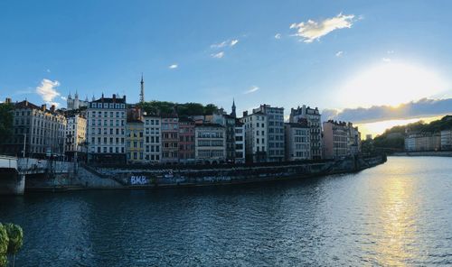 Buildings by river against sky in city