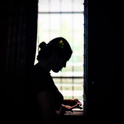 Portrait of silhouette man sitting on window at home