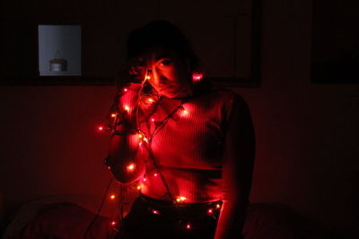 Portrait of woman with illuminated lights standing at home