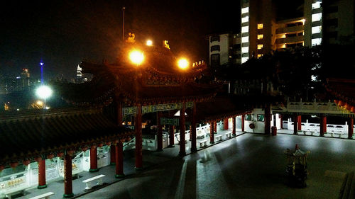 Illuminated street amidst buildings in city at night