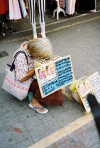 High angle view of girl sitting in city