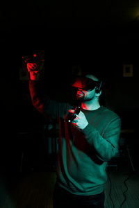 A man stands in a dark room wearing virtual reality gear and glasses