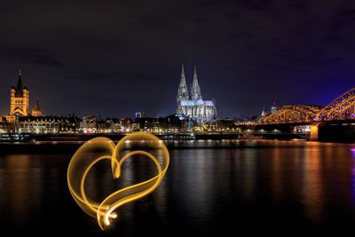 Light painting over river against sky in city at night