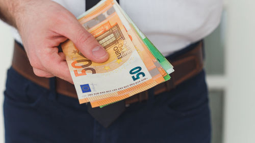 Midsection of man holding paper
