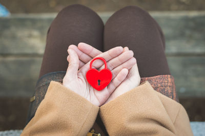 Low section of woman holding heart shape padlock