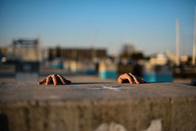 Close-up of hand against sky in city