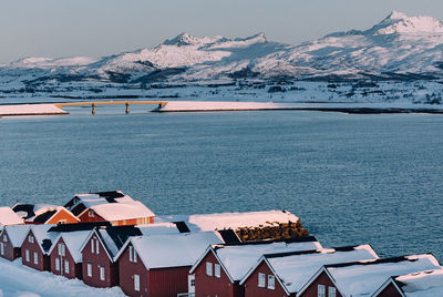 Scenic view of sea by snowcapped mountains against sky