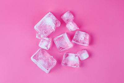 Directly above shot of ice cubes over pink background