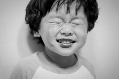 Close-up of boy with eyes closed against wall