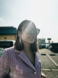 Portrait of young woman wearing sunglasses against sky