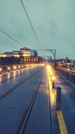 Illuminated railroad tracks against sky in city at night