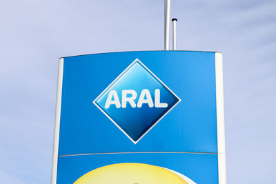 Low angle view of road sign against blue sky