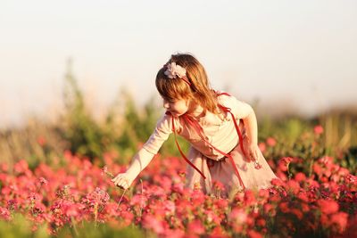 Low angle view of girl on flowering plant at field