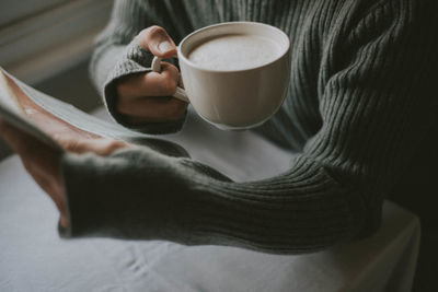 Midsection of man holding coffee cup