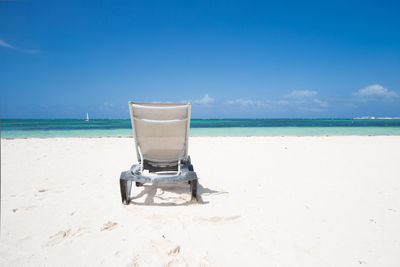 Deck chair on beach against sky
