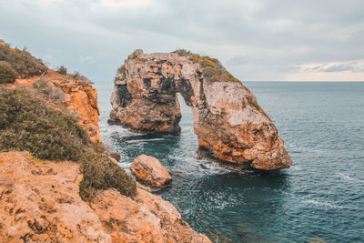 Rock formation in sea against sky