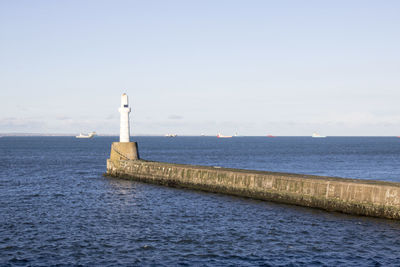 Lighthouse by sea against sky