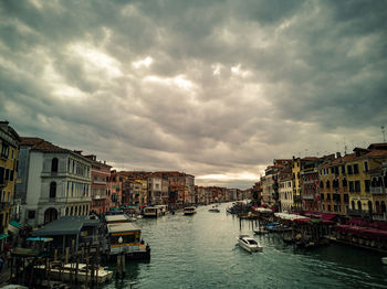 Boats in canal amidst buildings in city against sky