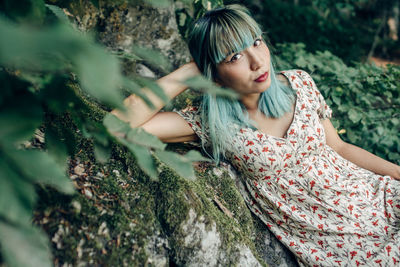 Portrait of young woman lying on tree