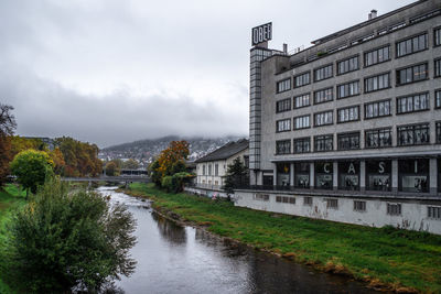 River by buildings in city against sky