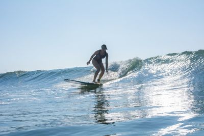 Full length of man surfing in sea against clear sky