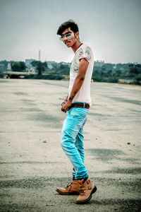 Portrait of young man wearing sunglasses standing against sky