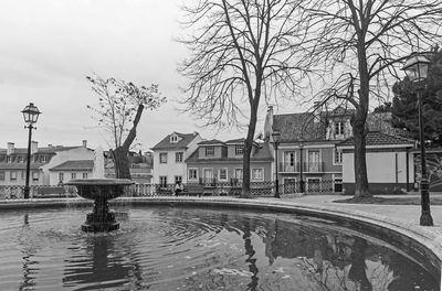 Canal by buildings in city against sky