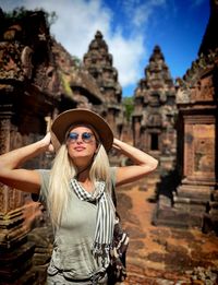 Portrait of young woman standing against building