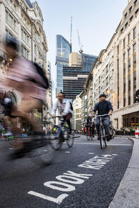 People cycling on road in city of london, uk