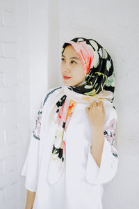 Portrait of woman standing against white wall