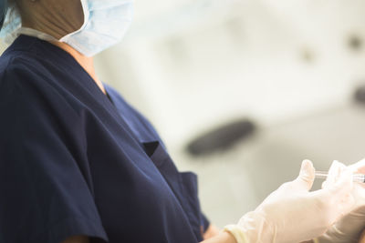 Midsection of surgeon with syringe in hospital