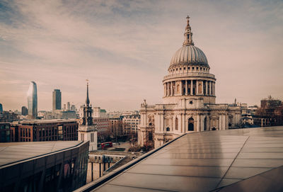 Buildings in city against cloudy sky