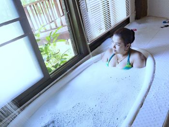 High angle view of thoughtful woman relaxing in bathtub at home