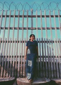 Portrait of smiling man standing by railing against fence