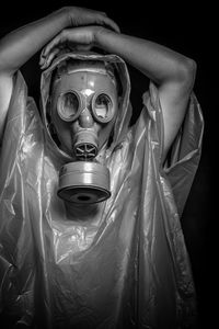 Man in raincoat wearing gas mask against black background