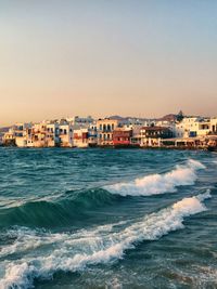 Sea by buildings in city against clear sky