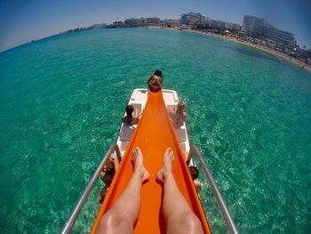 Low section of woman on slide in sea during sunny day