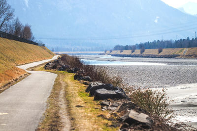 Road by river against sky during winter