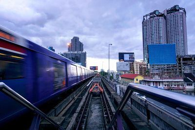 Railroad tracks amidst buildings in city against sky