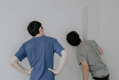 Two caucasian male plasterer man checks the evenness of the walls after puttying.