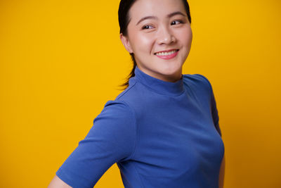 Portrait of smiling man standing against yellow background